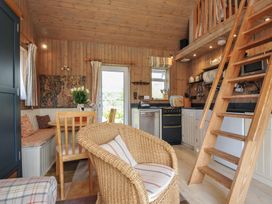 A living room with a kitchen area and stairs at Cartway Cabin in Port Isaac