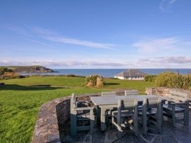A garden with a table and chairs overlooking the ocean at Upper Gren in Trebetherick