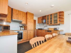 A kitchen with wooden cabinets and table at Upper Gren in Trebetherick