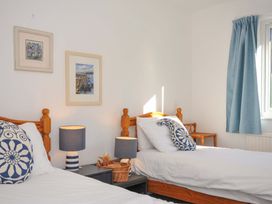 A bedroom with two beds, lamps, and artwork at Upper Gren in Trebetherick