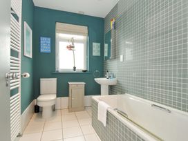 A bathroom featuring a bathtub, toilet, sink, and window at The Point in Polzeath