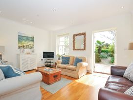 A living room with sofas a wooden chest coffee table a white cabinet a television and an open door to a garden at Lowenna Manor 3 Rock