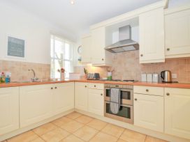 A kitchen with cream cabinets, a stainless steel double oven, a stove, a kettle, and a window with blinds at Lowenna Manor 3 in Rock