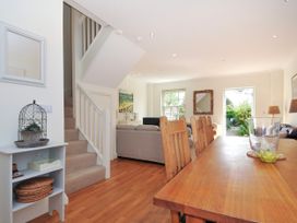 A dining area with wooden chairs and table next to a living room with sofas and a staircase at Lowenna Manor 3 in Rock