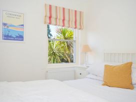 A bedroom with a white bed and mustard pillow next to a window with striped blind and a bedside table with lamp at Lowenna Manor 3 in Rock