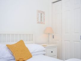 A bedroom with a white bed with a yellow pillow a white nightstand with a lamp and a small mirror on the wall at Lowenna Manor 3 in Rock