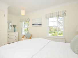A bedroom with a bed a chest of drawers a chair two windows and a painting at Lowenna Manor 3 Rock
