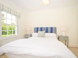 A bedroom with a bed with blue headboard and white bedding between two bedside tables with lamps Lowenna Manor 3 Rock