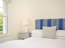 A bedroom with a bed featuring a blue patterned headboard a bedside table with a lamp and a window at Lowenna Manor 3 Rock
