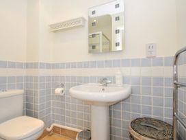 A bathroom with a toilet sink mirror and tiled walls at Lowenna Manor 3 in Rock