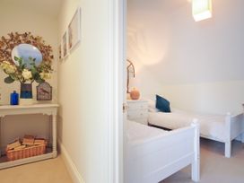 A hallway with a table holding flowers and a mirror next to a bedroom with two beds and a nightstand at Lowenna Manor 3 in Rock