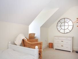 A bedroom with a white bed frame wicker chair white dresser and round mirror at Lowenna Manor 3 in Rock