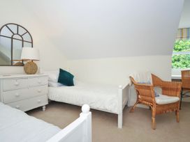 A bedroom with two single beds a white dresser a wicker chair and a window at Lowenna Manor 3 in Rock