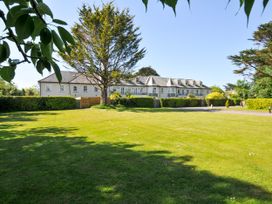 A large lawn with trees and hedges in front of a two story building at Lowenna Manor 3 in Rock