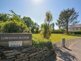 A driveway entrance with a sign reading Lowenna Manor private drive a lawn with trees and a house in the background at Lowenna Manor 3 Rock