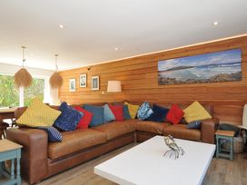 A living room with a brown sofa and colorful cushions at Beaches in Polzeath