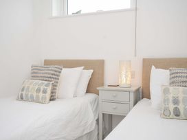 A bedroom with two beds and a lamp on a bedside table at Stepper Point in Polzeath