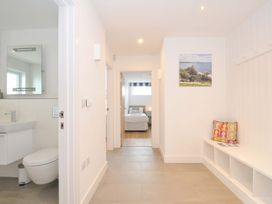 A hallway with a sink, toilet, and wall art at Stepper Point in Polzeath