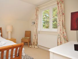 A bedroom with a bed, nightstand, chair and window at Sandy Lodge Rock