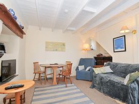 A living room with a sofa and dining table at Coppingers Cottage in Polzeath