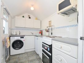 A kitchen with a washing machine and stove at Coppingers Cottage Polzeath