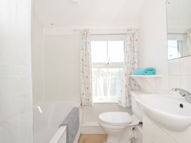 A bathroom with a bathtub, toilet, and sink at Coppingers Cottage in Polzeath