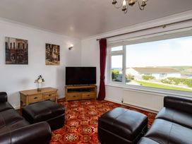 A living room with a television and views outside at Hillview in Polzeath