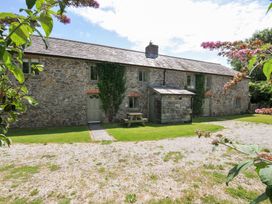 A stone house with a table and bench in the garden at Orchard Cottage in Polzeath