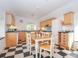 A kitchen with wooden cabinets and a table at Orchard Cottage in Polzeath