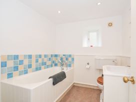 A bathroom with a bathtub, toilet, and sink at Orchard Cottage in Polzeath