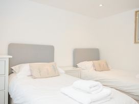 A bedroom with two beds and a bedside table at Orchard Cottage Polzeath
