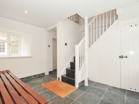 A hallway with a staircase and a bench at Orchard Cottage in Polzeath