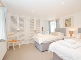 A bedroom with two beds and a chair at Orchard Cottage in Polzeath