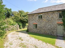 A stone building with windows and a gate at Orchard Cottage in Polzeath