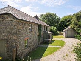 An outdoor view of a stone house and garage at Orchard Cottage in Polzeath