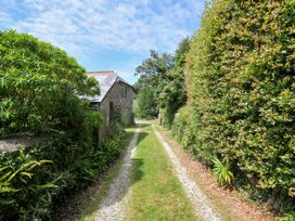 A path leading to a house surrounded by hedges and plants at Orchard Cottage in Polzeath