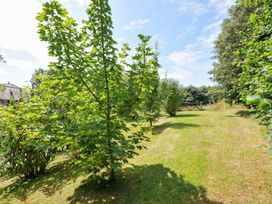 A garden with trees and grass at Orchard Cottage Polzeath