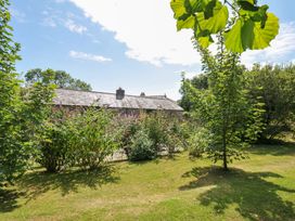 A view of a building surrounded by trees and bushes at Orchard Cottage in Polzeath