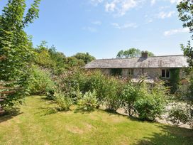 A garden with a house and greenery at Orchard Cottage in Polzeath