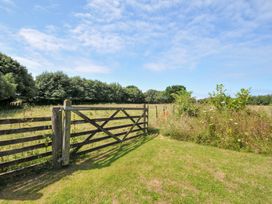 A gate leading to a grassy field with trees at Orchard Cottage in Polzeath