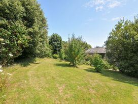 A garden with trees and a path leading to a shed at Orchard Cottage in Polzeath