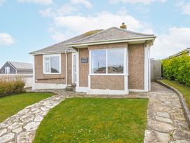 A bungalow with a stone pathway and grass at Hillcroft Bungalow in Daymer Bay