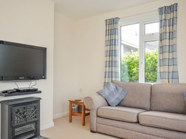 A living room with a television and sofa at Hillcroft Bungalow in Daymer Bay