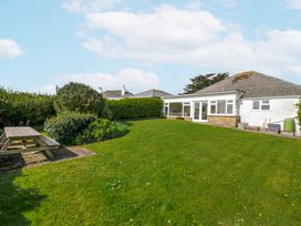 A garden with a picnic table and a bungalow at Hillcroft Bungalow in Daymer Bay