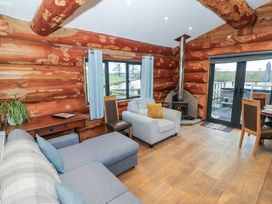 A living room with a sofa, fireplace, and table at Cedar Cabin at Salford Court Farm Fishing Cabins near Clifton Upon Teme