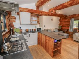 A kitchen with wooden cabinets and a seating area at Cedar Cabin at Salford Court Farm Fishing Cabins Near Clifton Upon Teme