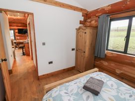 A bedroom with a bed and wardrobe at Cedar Cabin at Salford Court Farm Fishing Cabins near Clifton Upon Teme