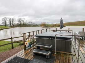 An outdoor area with a hot tub and views of the lake at Cedar Cabin at Salford Court Farm Fishing Cabins near Clifton Upon Teme