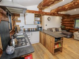 A kitchen with a stove, sink, and sofa at Douglas Cabin at Salford Court Farm Fishing Cabins Near Clifton Upon Teme