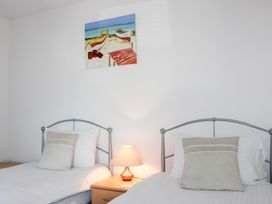 A bedroom with two beds and a painting of boats at Gilly's Cottage in Hope Cove